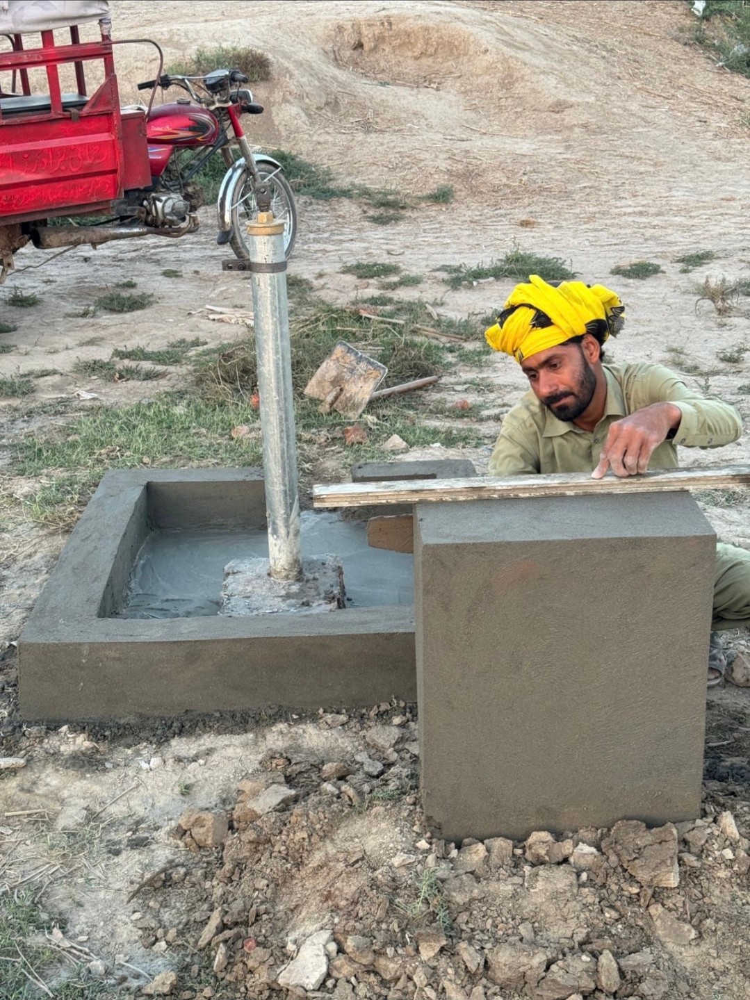A local worker constructing a community hand-pump water point