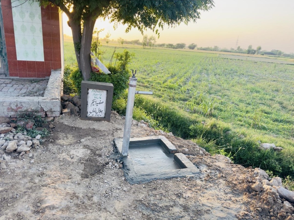 A completed community hand-pump water point beside a rural home