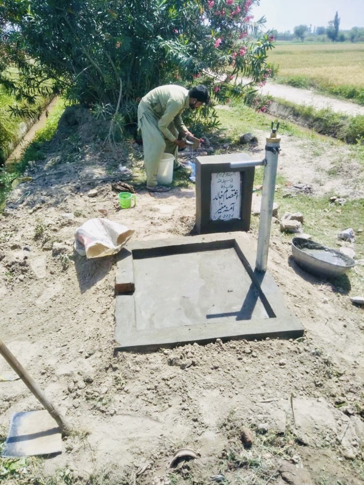 A community member using a completed hand-pump water point