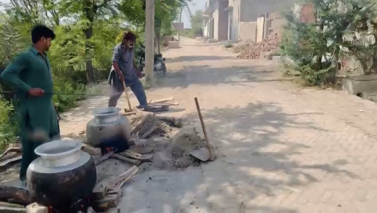 Large cooking pots over an open wood fire while meals are prepared for a community