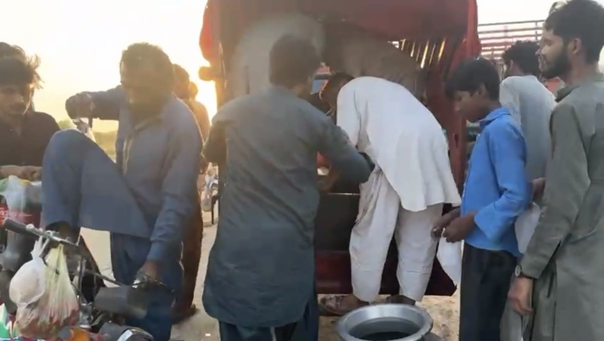 Community members gathering at a vehicle as food is handed out