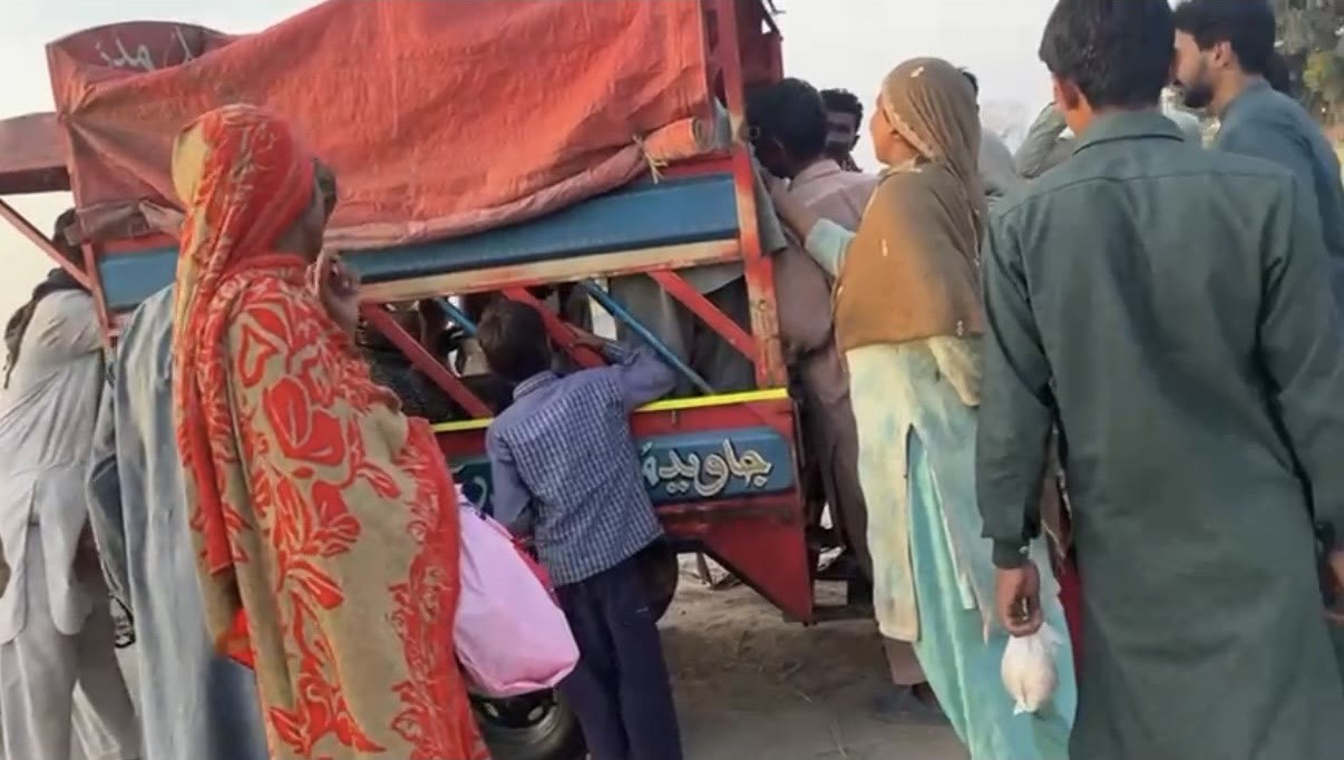 Families waiting together as food is distributed from a cart