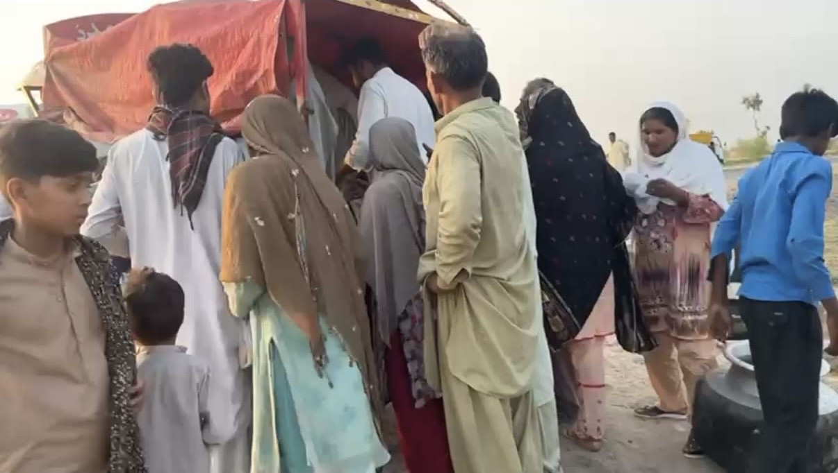 Women, men and children queuing as food is served to the community
