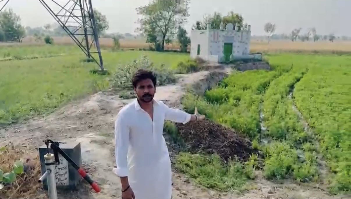 A hand-pump water well installed beside farmland