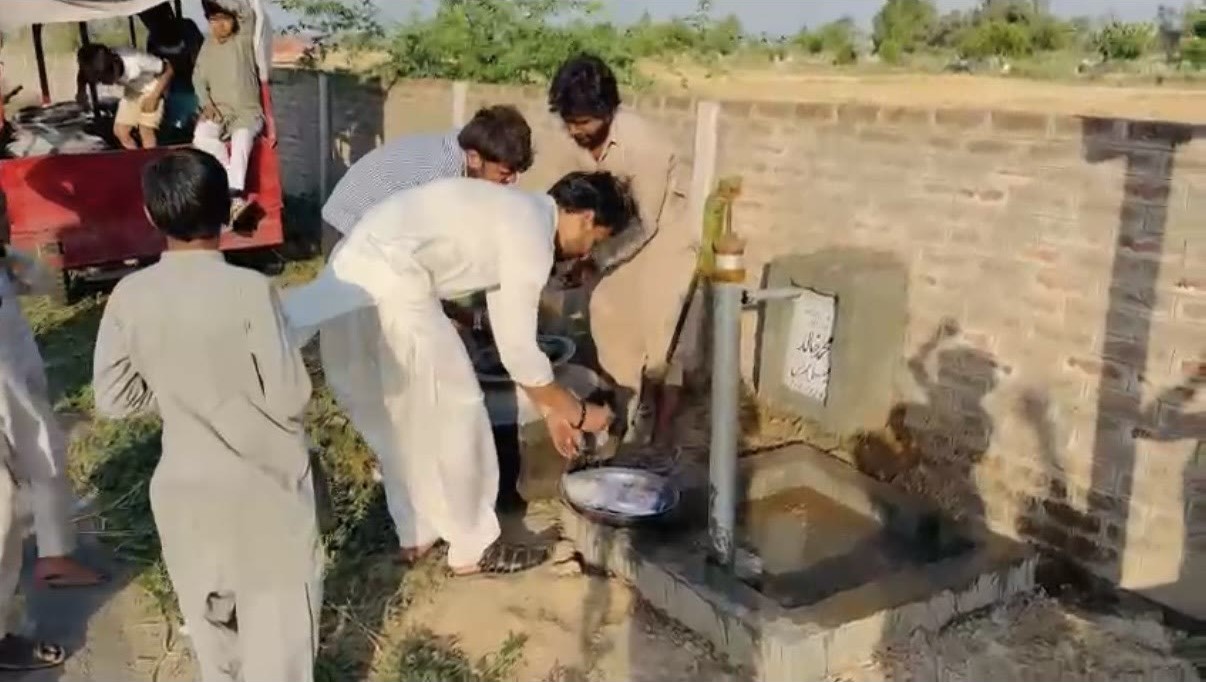 A newly completed community hand-pump water well being used
