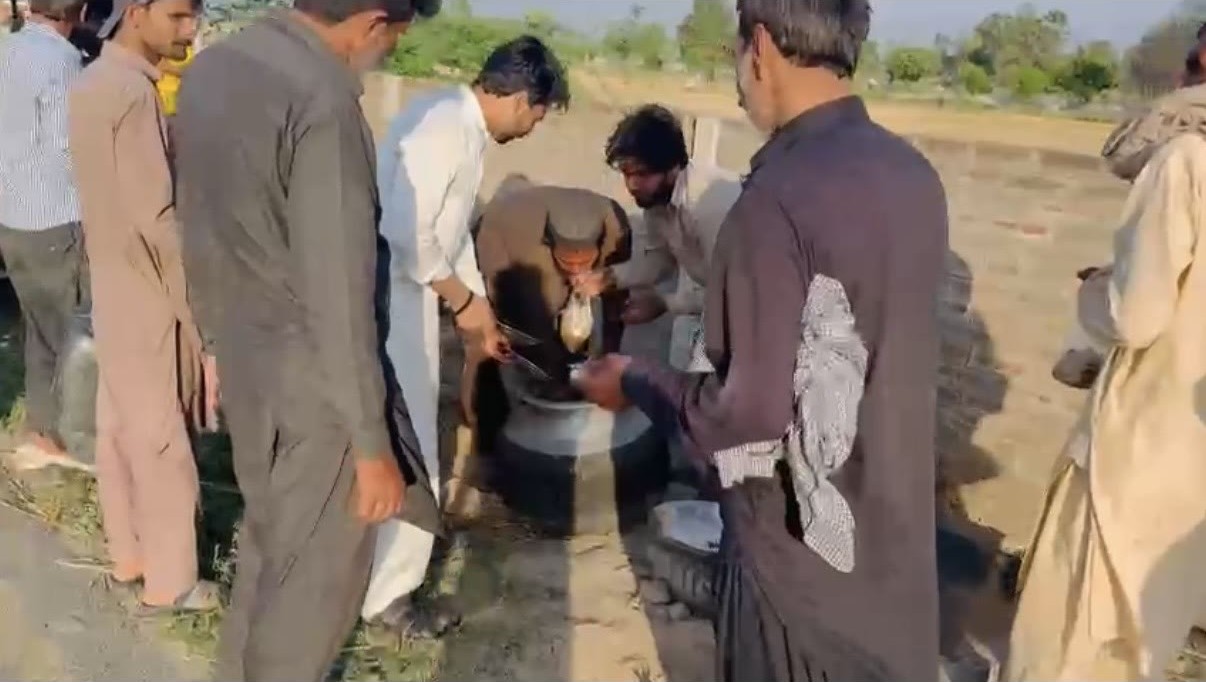 Community members drinking water from a completed hand-pump well