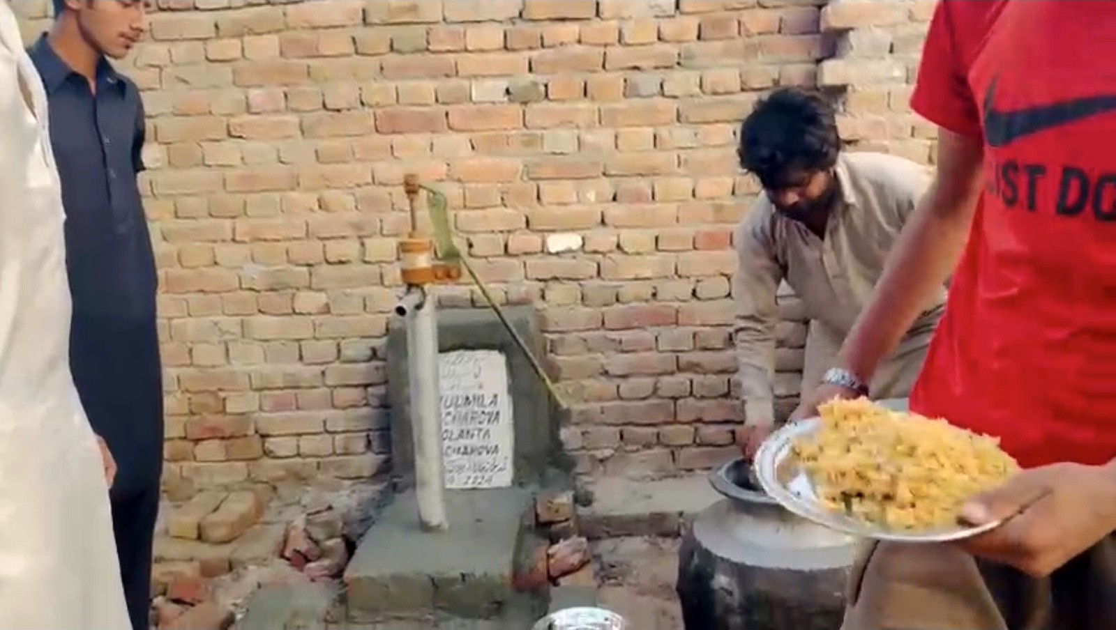 Food being served beside a hand-pump water point at a community