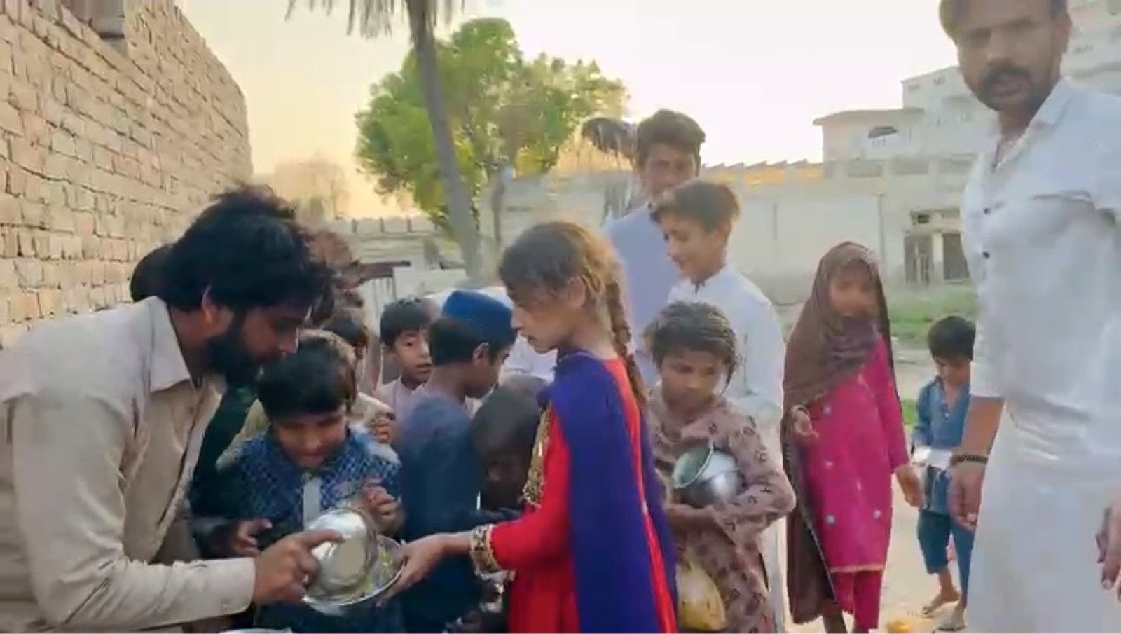 Children waiting with bowls as food is portioned out