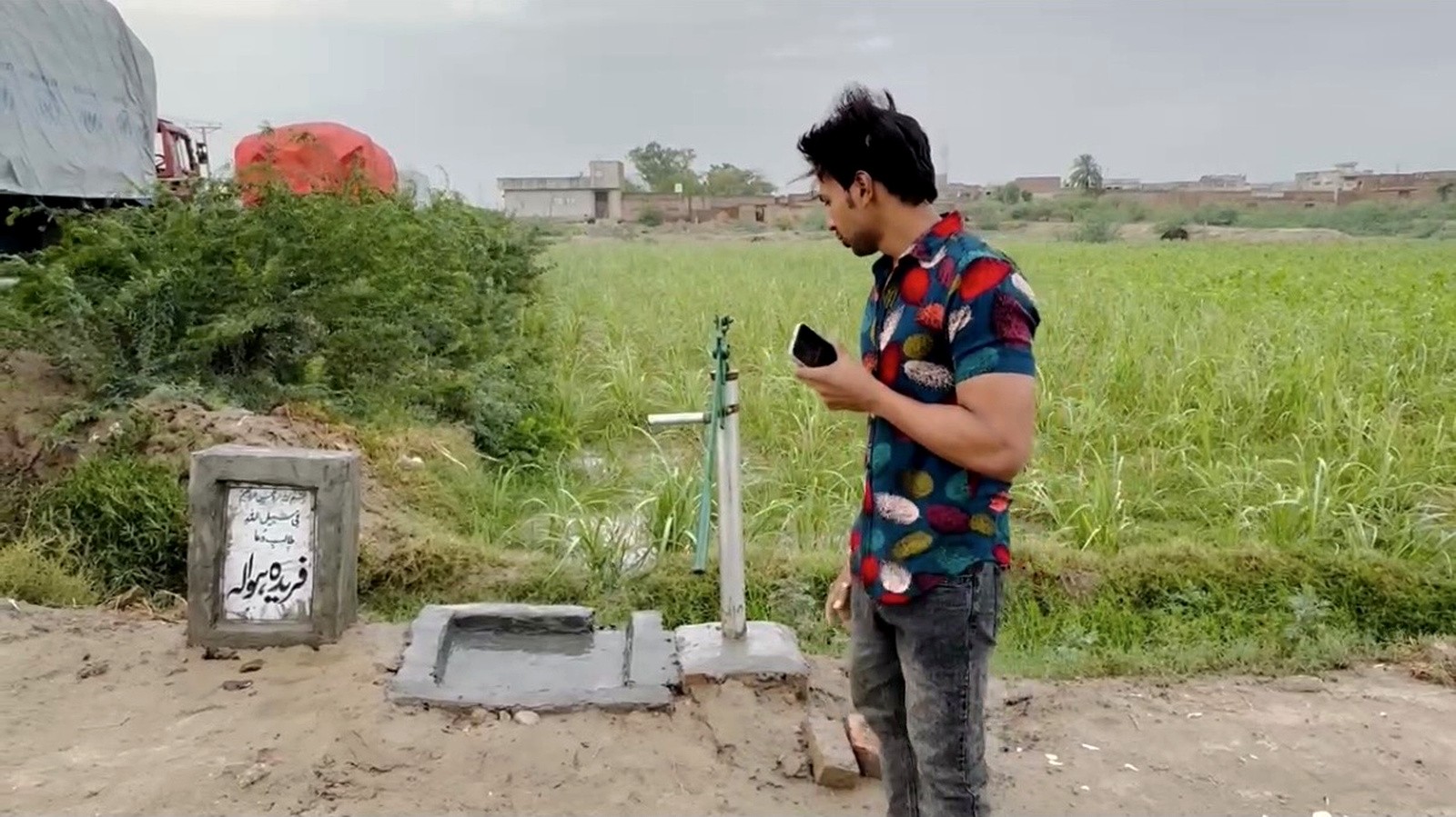 A newly installed hand-pump water point beside green farmland