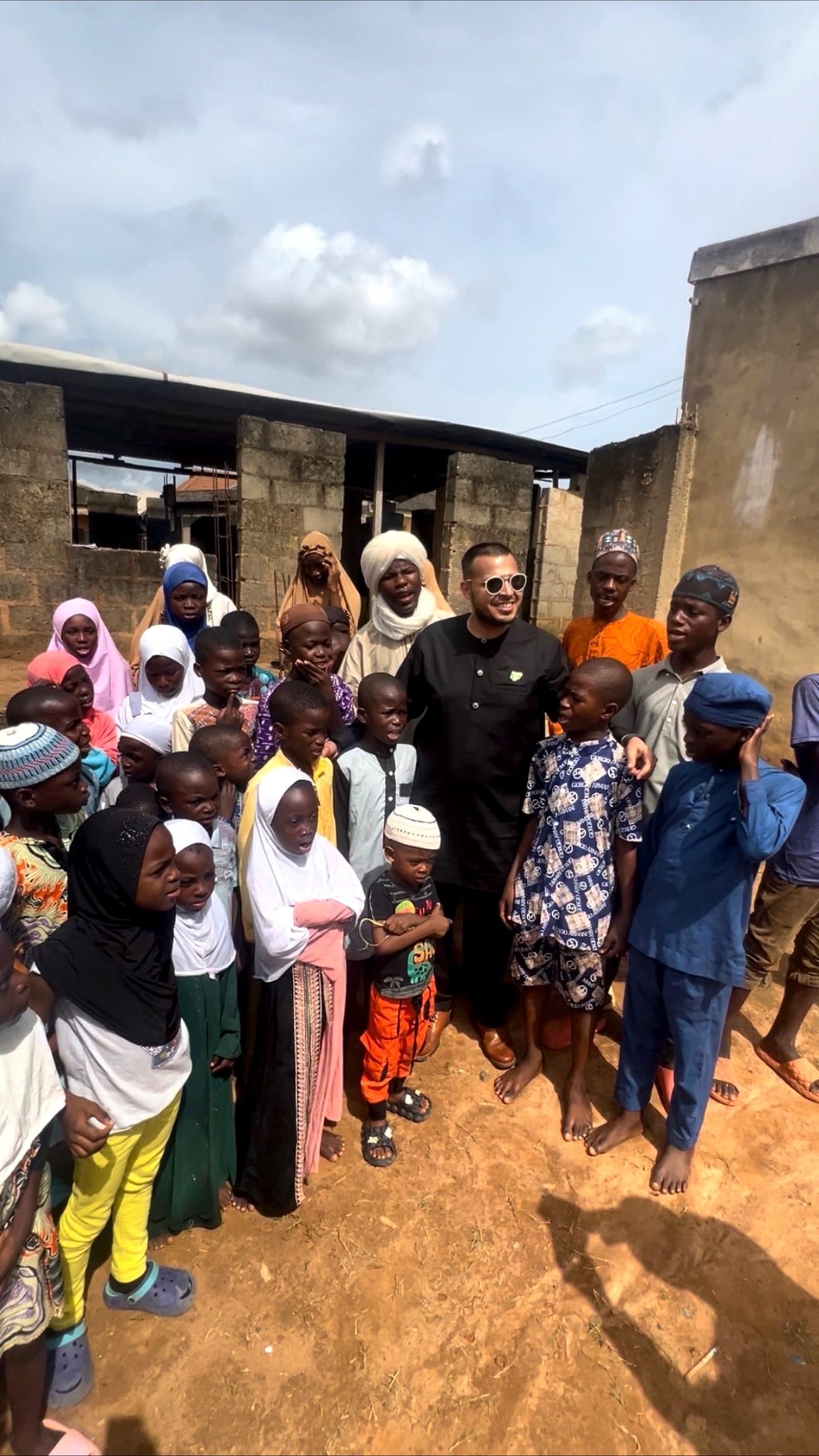 A man standing with a large group of children outside a school building