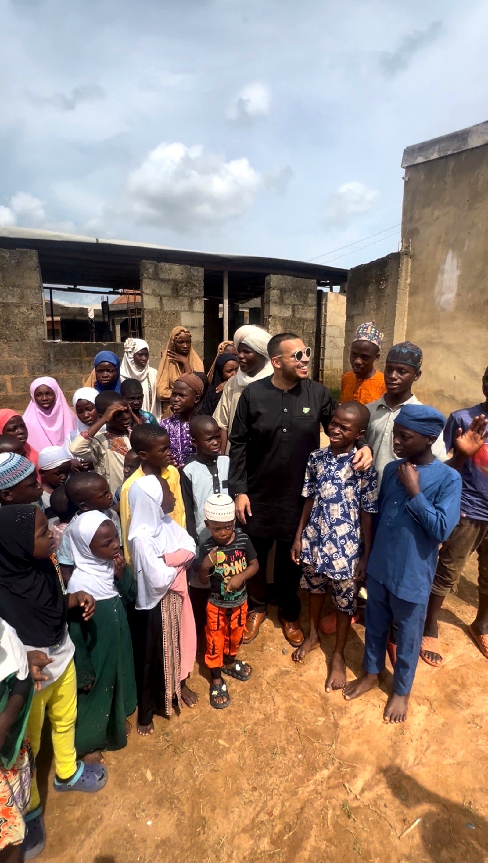 Children gathered around a visitor outside a community school