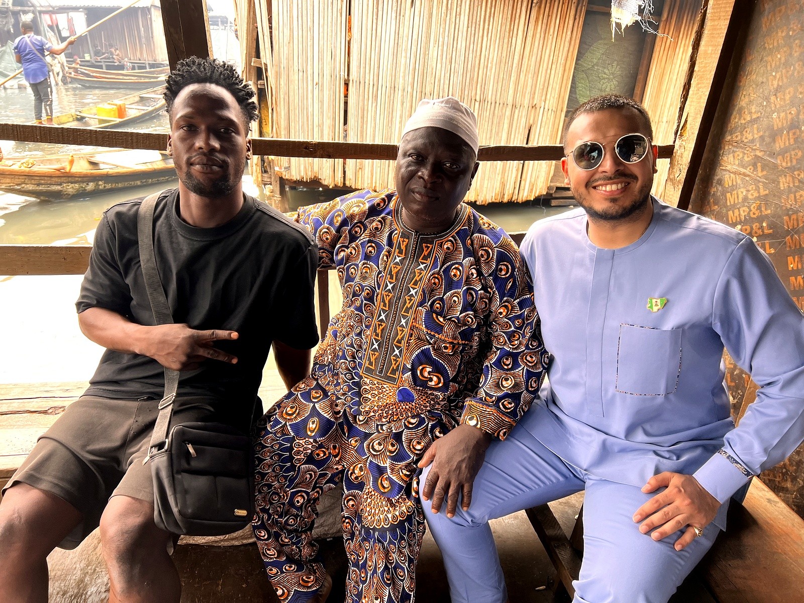 Three men seated together at a waterside community settlement