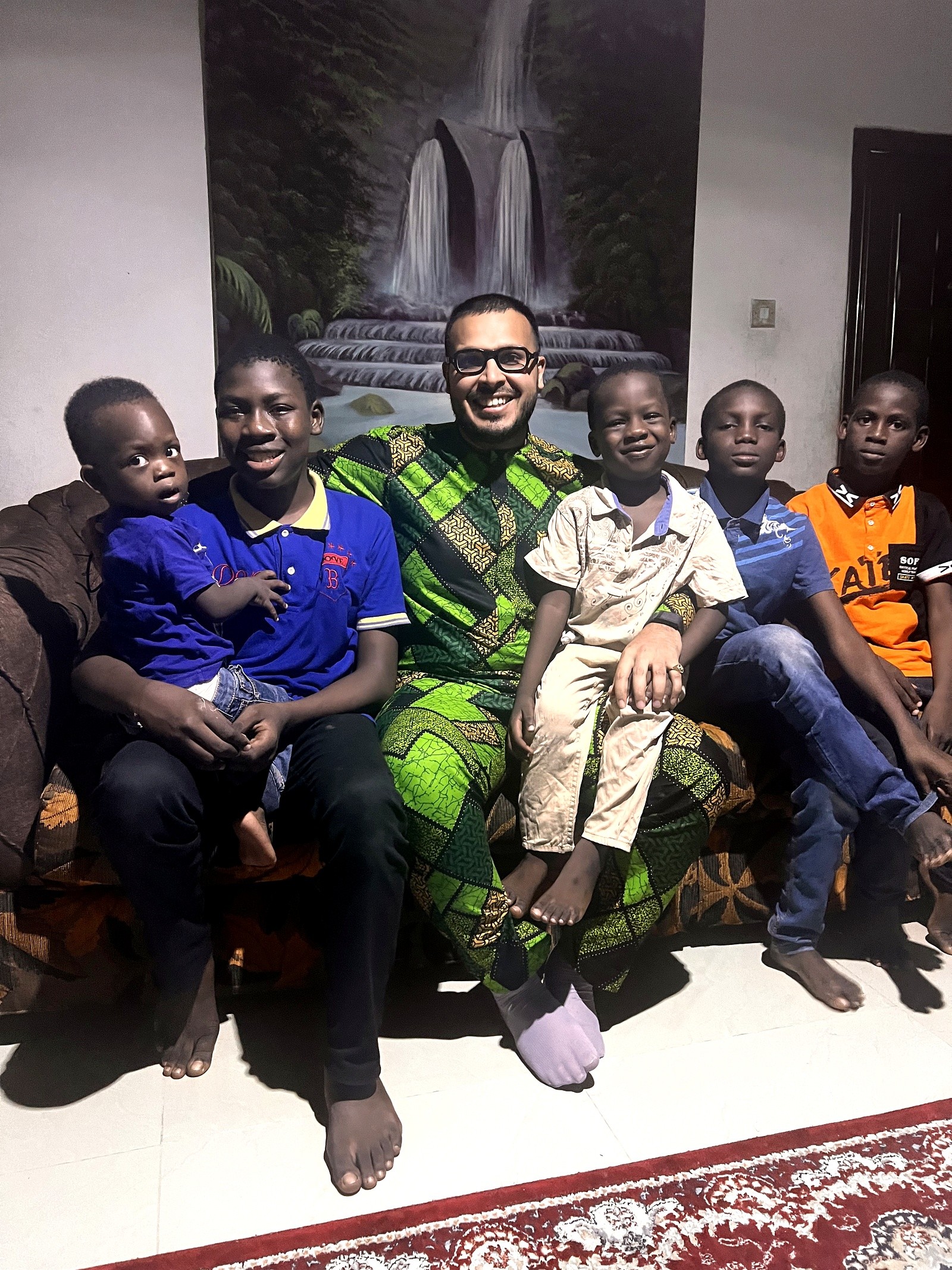 A man seated with a group of children in the evening