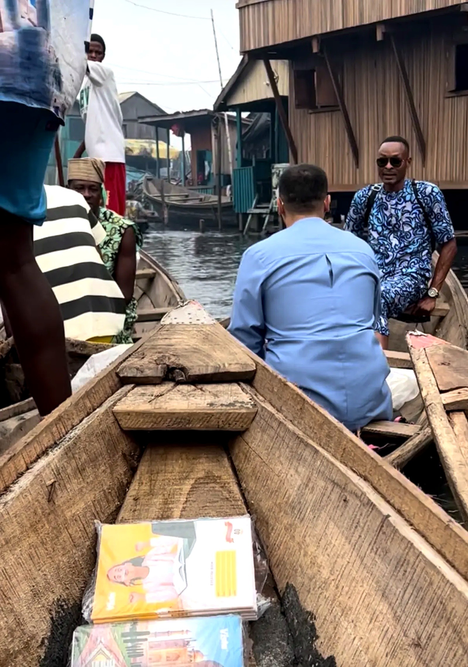 A canoe carrying school books moving between stilt houses on the water