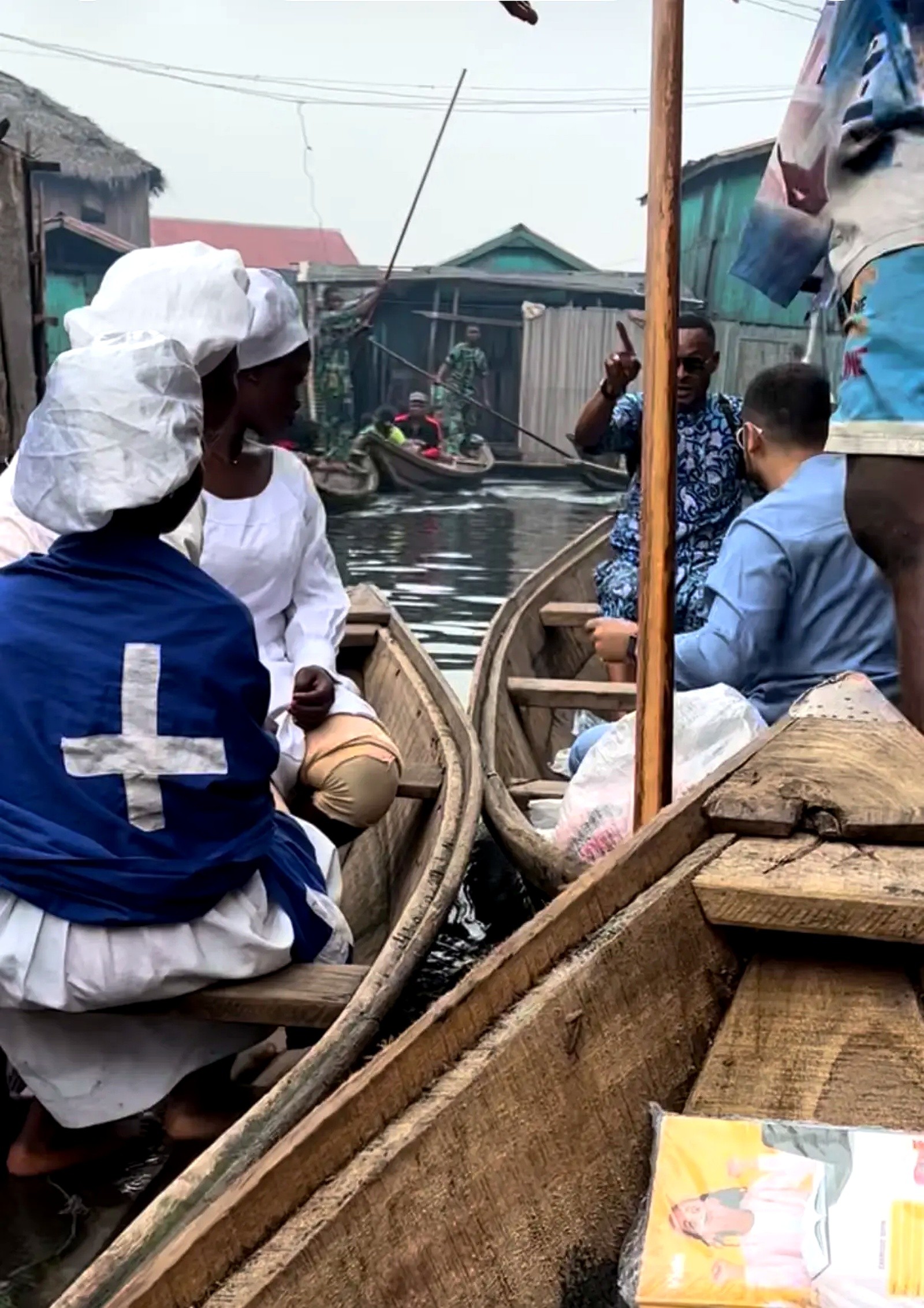 People in canoes gathered together on the water in a stilt village