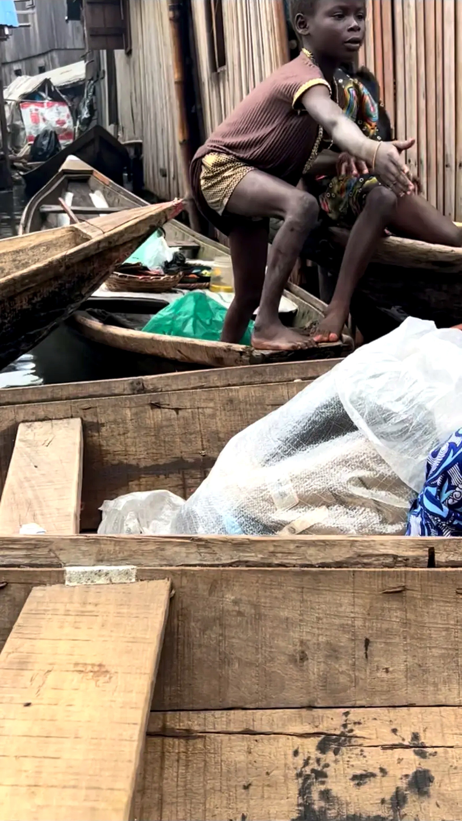 A child standing in a wooden canoe beside supplies