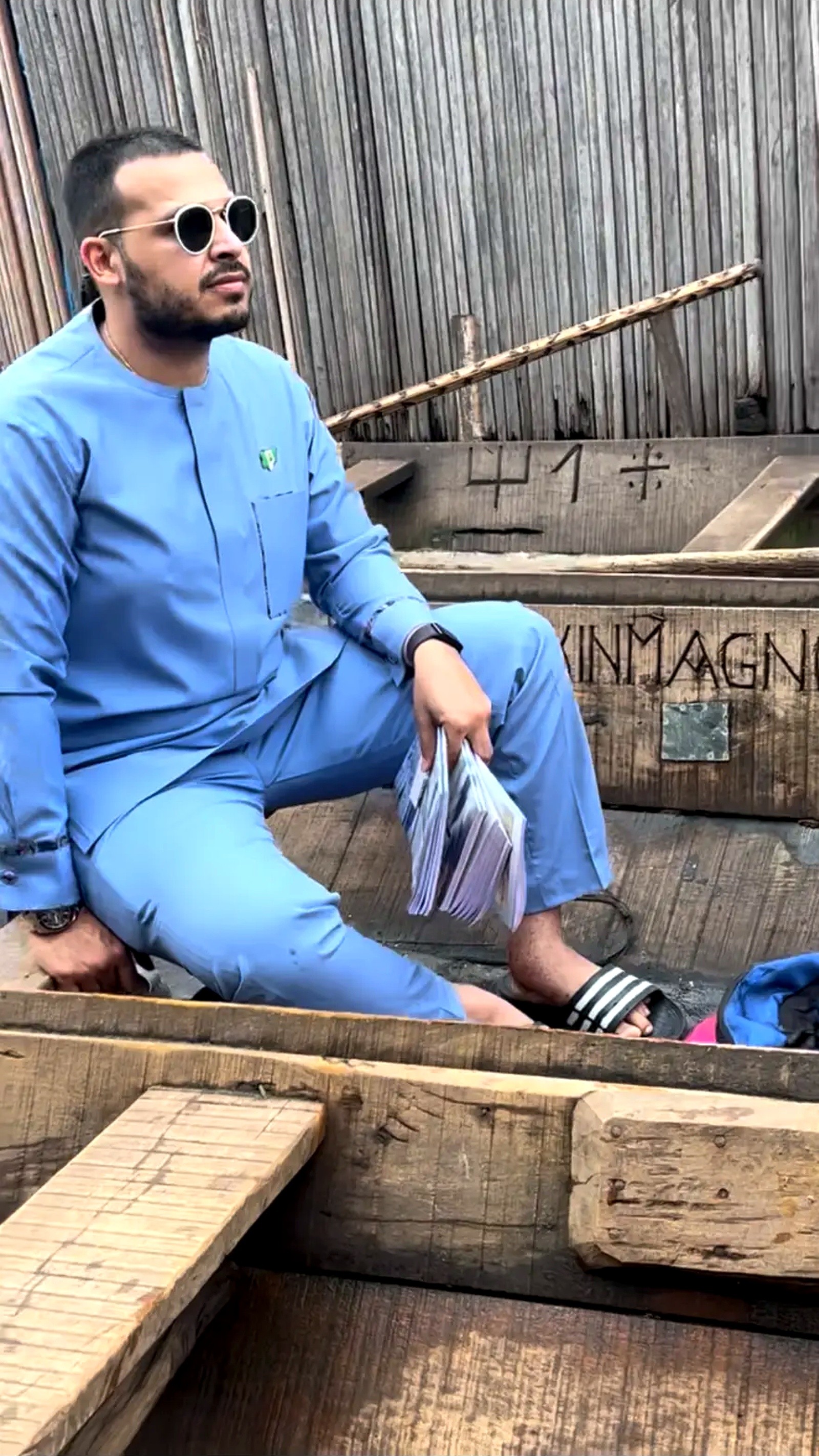 A man seated in a canoe holding a stack of exercise books