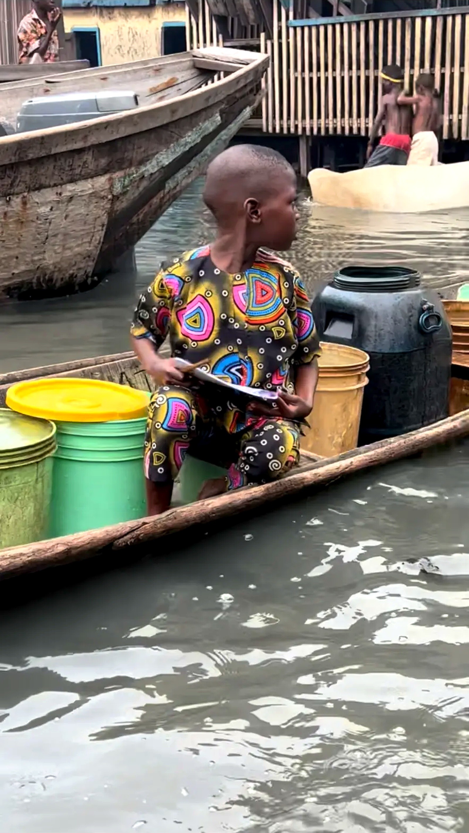 A child seated in a canoe holding a new exercise book