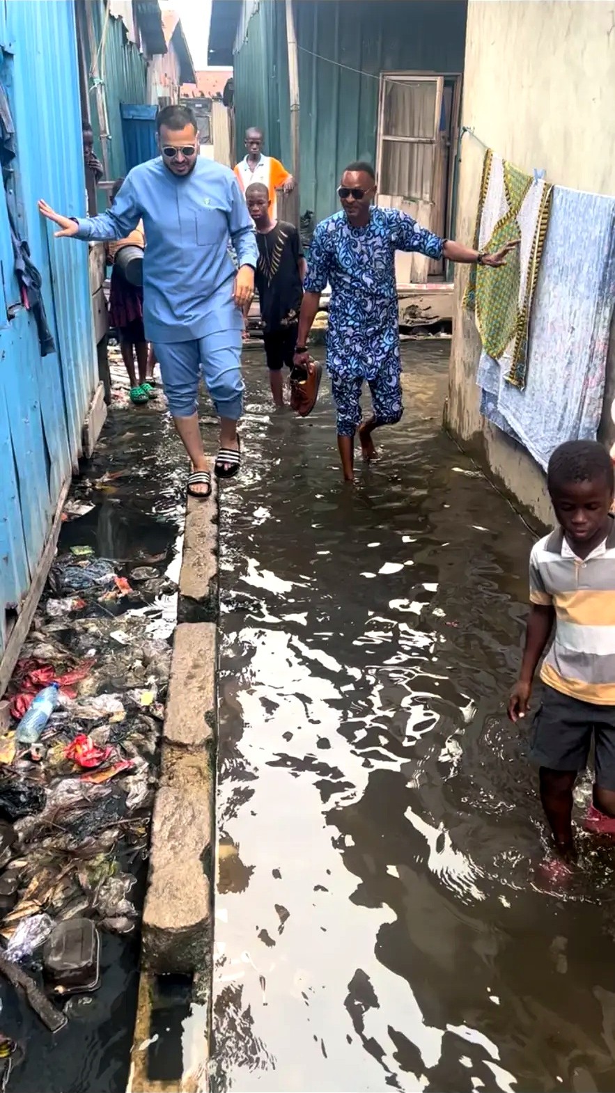 Men walking through shallow water between homes in a waterside community