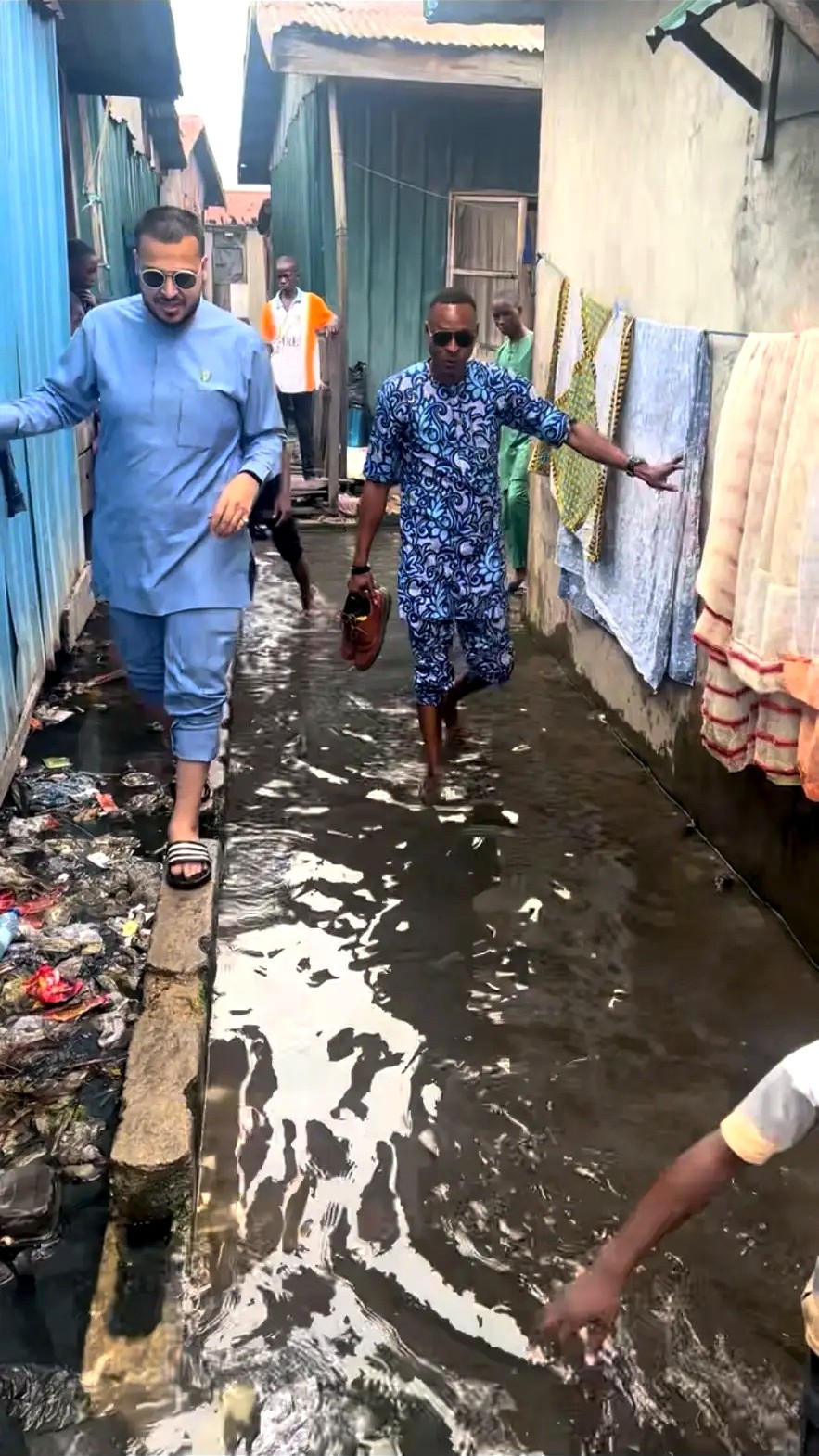 Men walking through a flooded walkway between homes in a waterside community