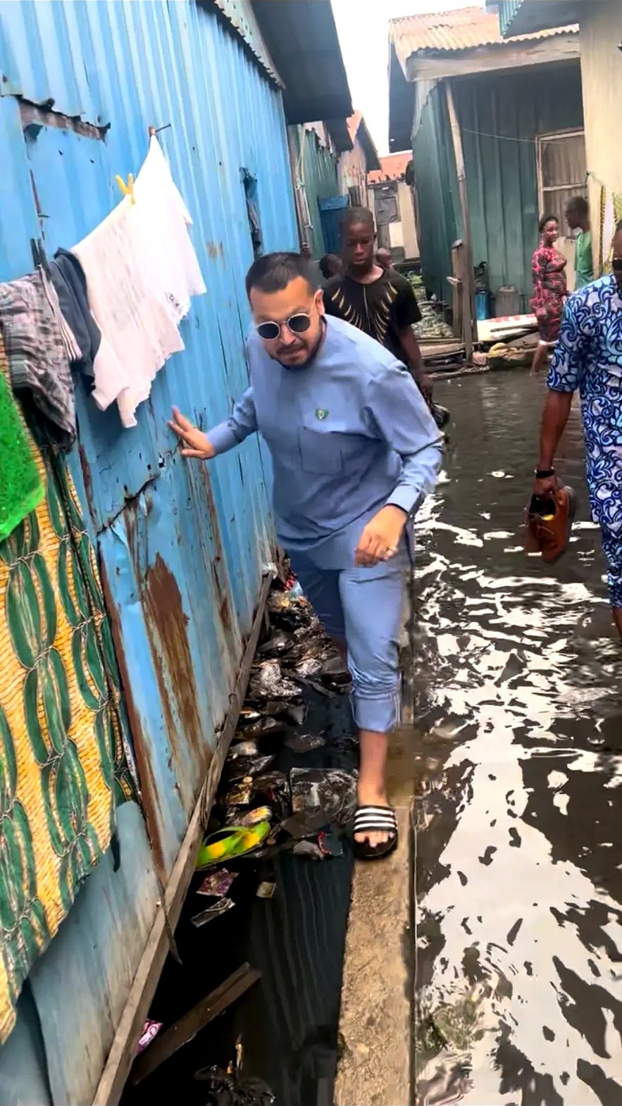 A man balancing along a narrow path beside water and homes