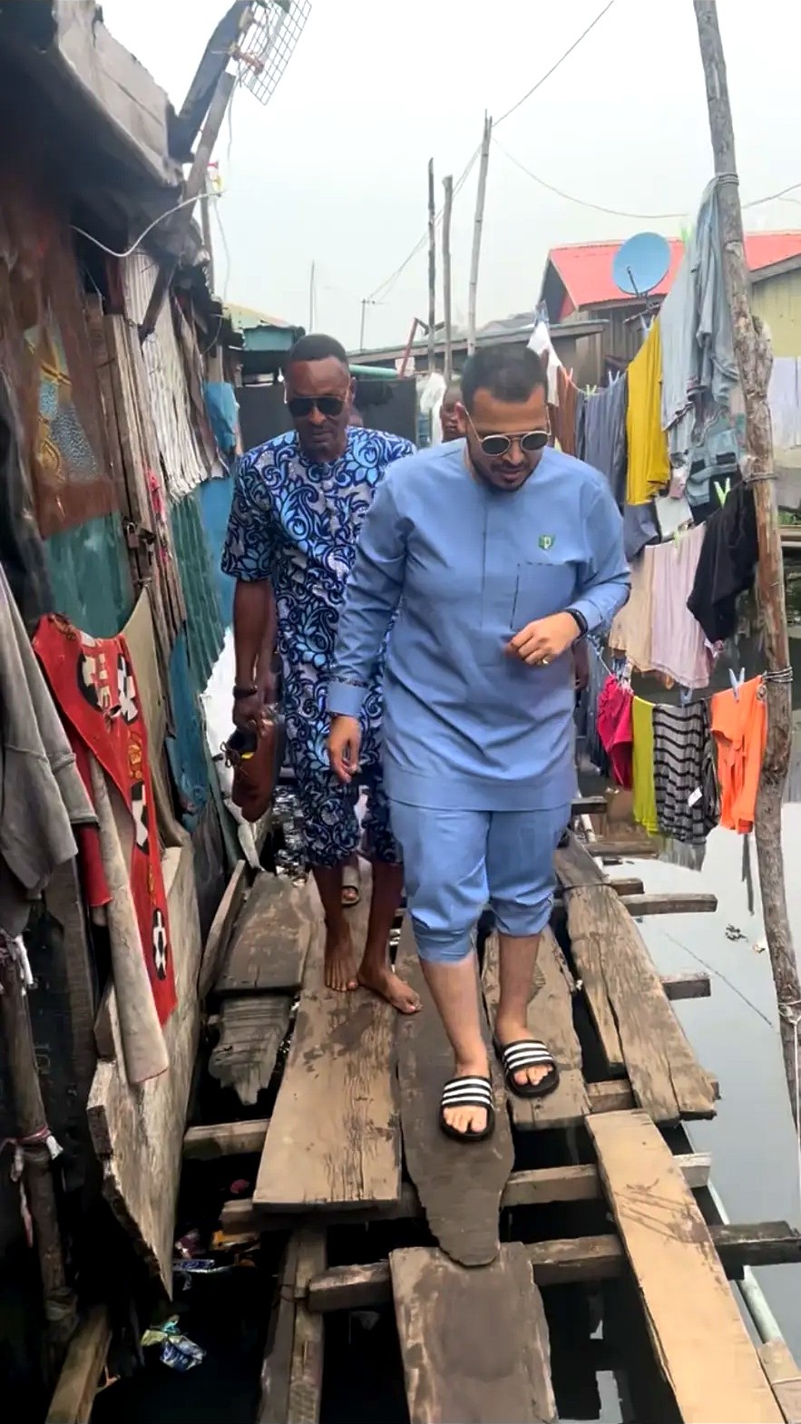 Men walking along wooden boards through a waterside village