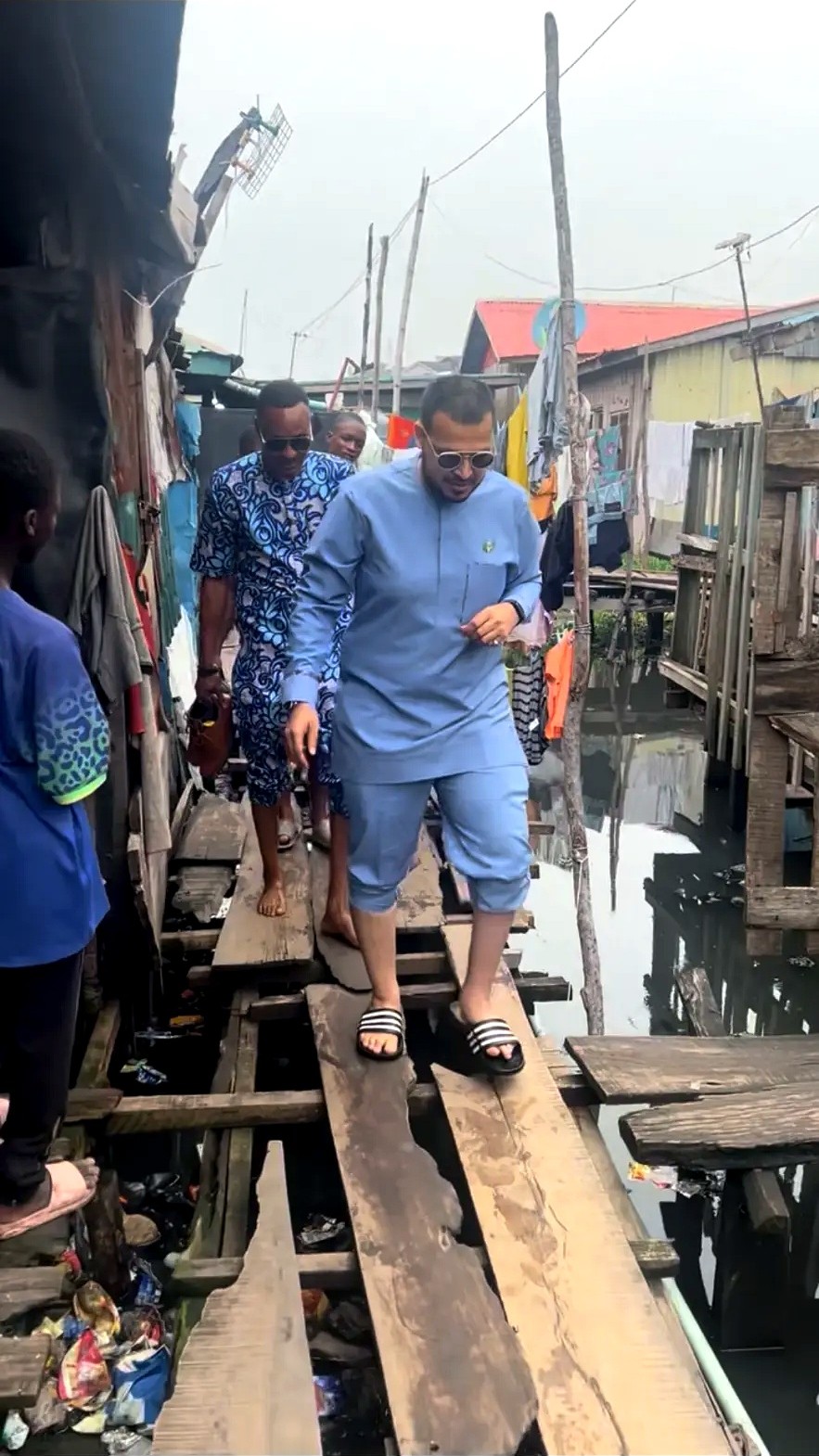 Men walking carefully on boards through a waterside residential area