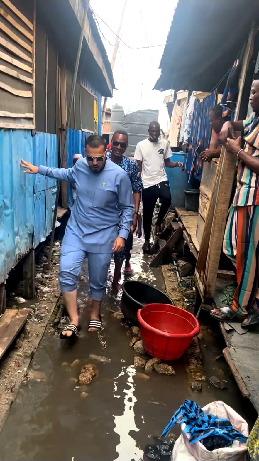 A group walking through a narrow waterside lane with homes on both sides