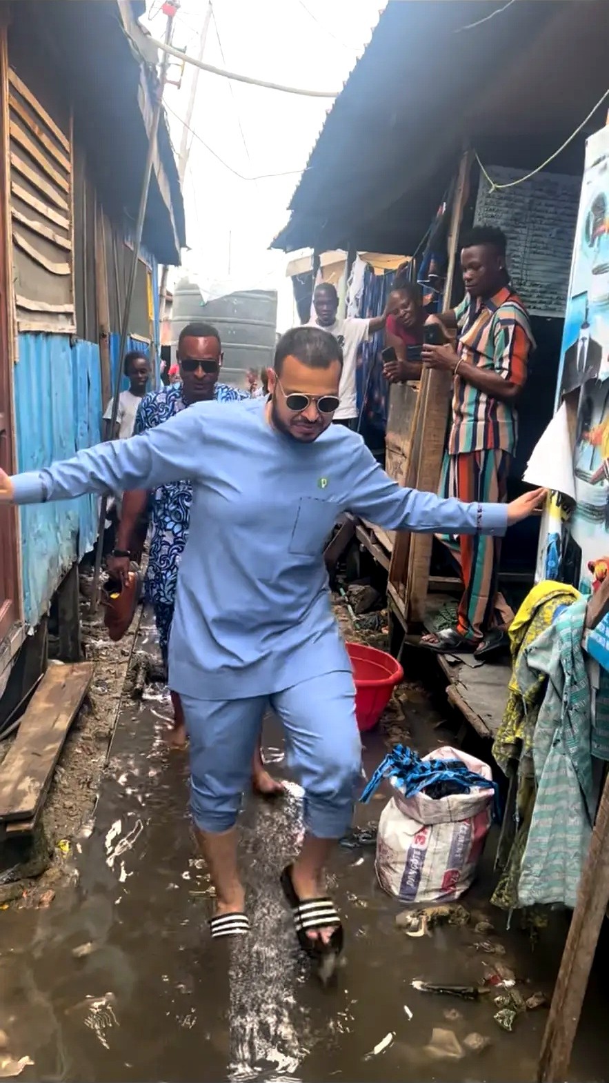Men moving through a waterside community while residents look on